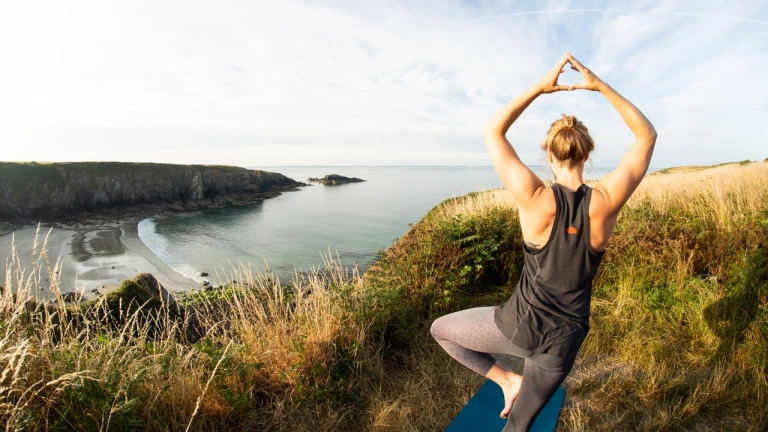 Person doing yoga overlooking beach.